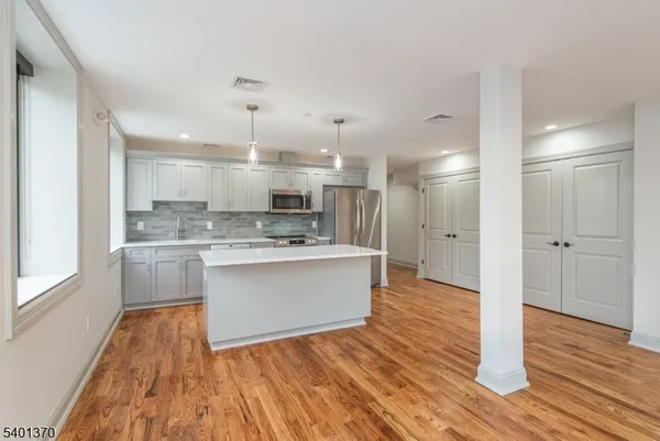 a large kitchen with a refrigerator a sink dishwasher a stove and white cabinets with wooden floor