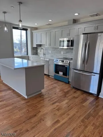 a kitchen with stainless steel appliances granite countertop a refrigerator a stove a sink and a microwave