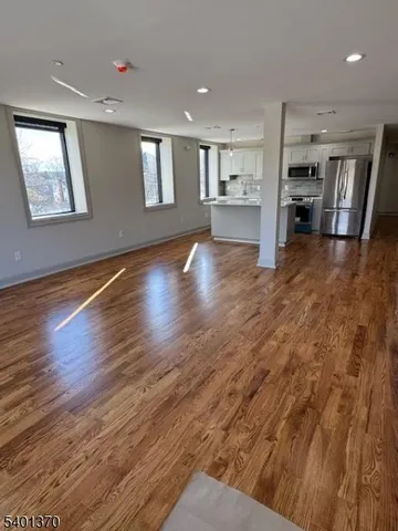 a view of a living room with kitchen furniture and wooden floor