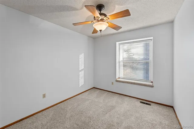 an empty room with a window and a ceiling fan