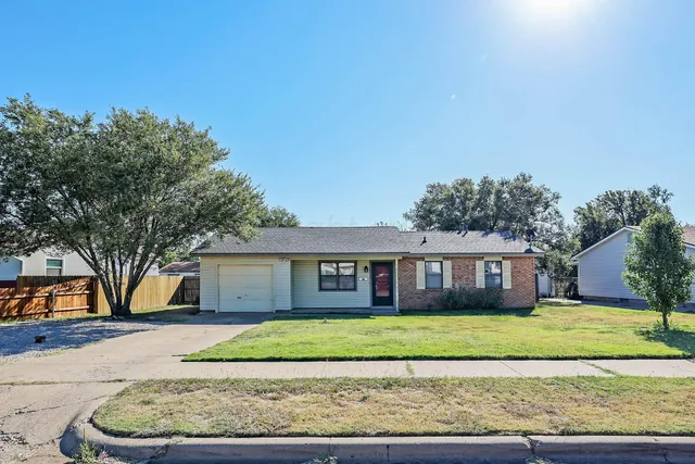 a front view of a house with a garden and tree
