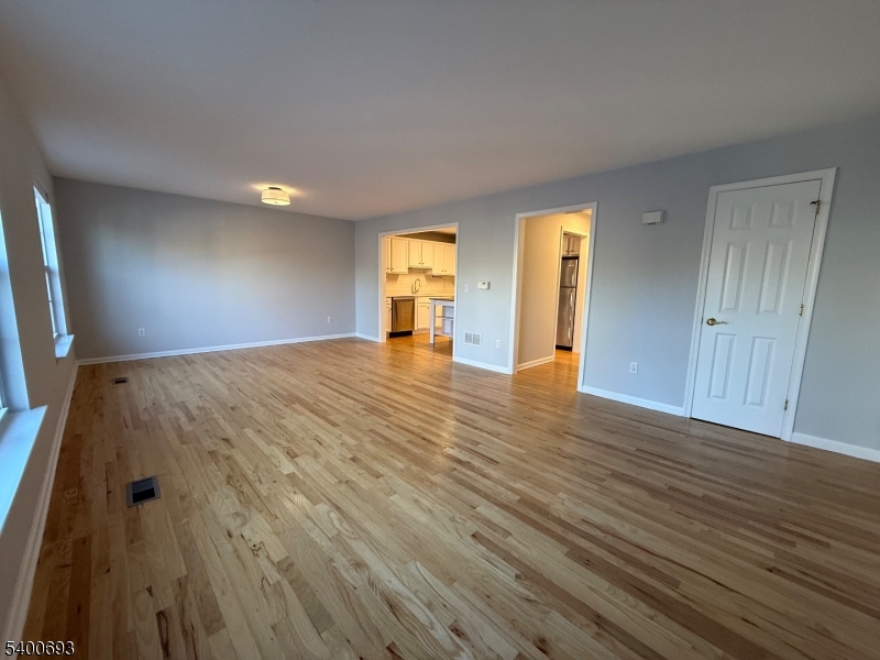 53 Division Avenue, Unit A5 New Providence, NJ 07901 - Photo 2 of 10 a view of an empty room with wooden floor and a window