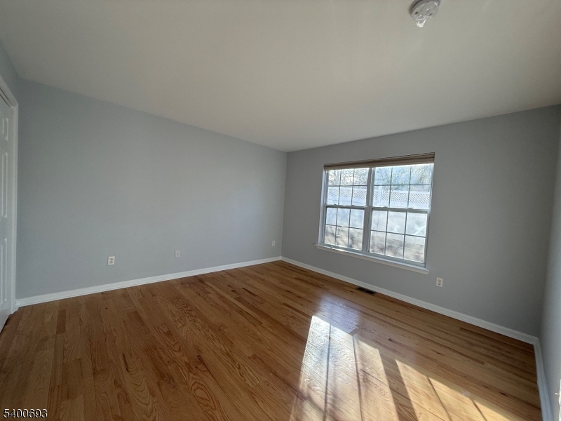 53 Division Avenue, Unit A5 New Providence, NJ 07901 - Photo 8 of 10 a view of an empty room with wooden floor and a window