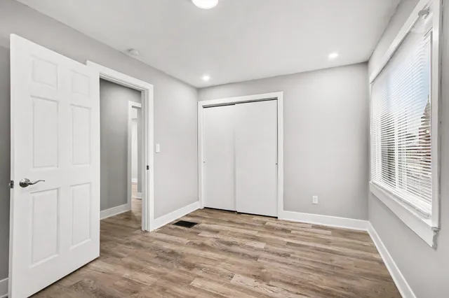 a view of empty room with wooden floor and fan