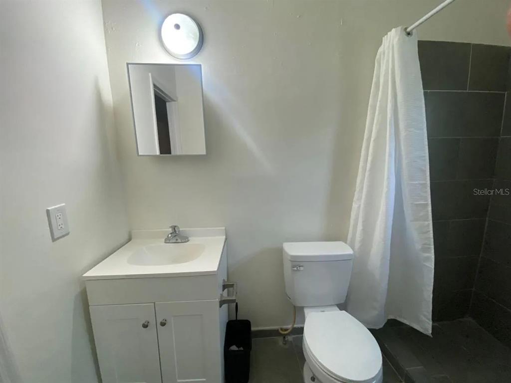4427 Raleigh Street Orlando, FL 32811 - Photo 10 of 31 a bathroom with a toilet sink and mirror