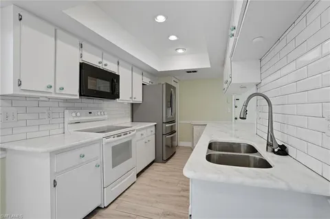 a kitchen with white cabinets sink and white appliances