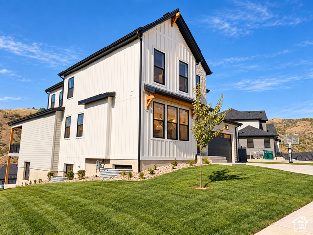 1595 West Canyon Rim Road, Unit 630 Lehi, UT 84048 - Photo 3 of 41 Modern farmhouse exterior featuring vertical board and batten siding, dark trim, a stone chimney, and a multi-level design. Lighting enhanced with ai.