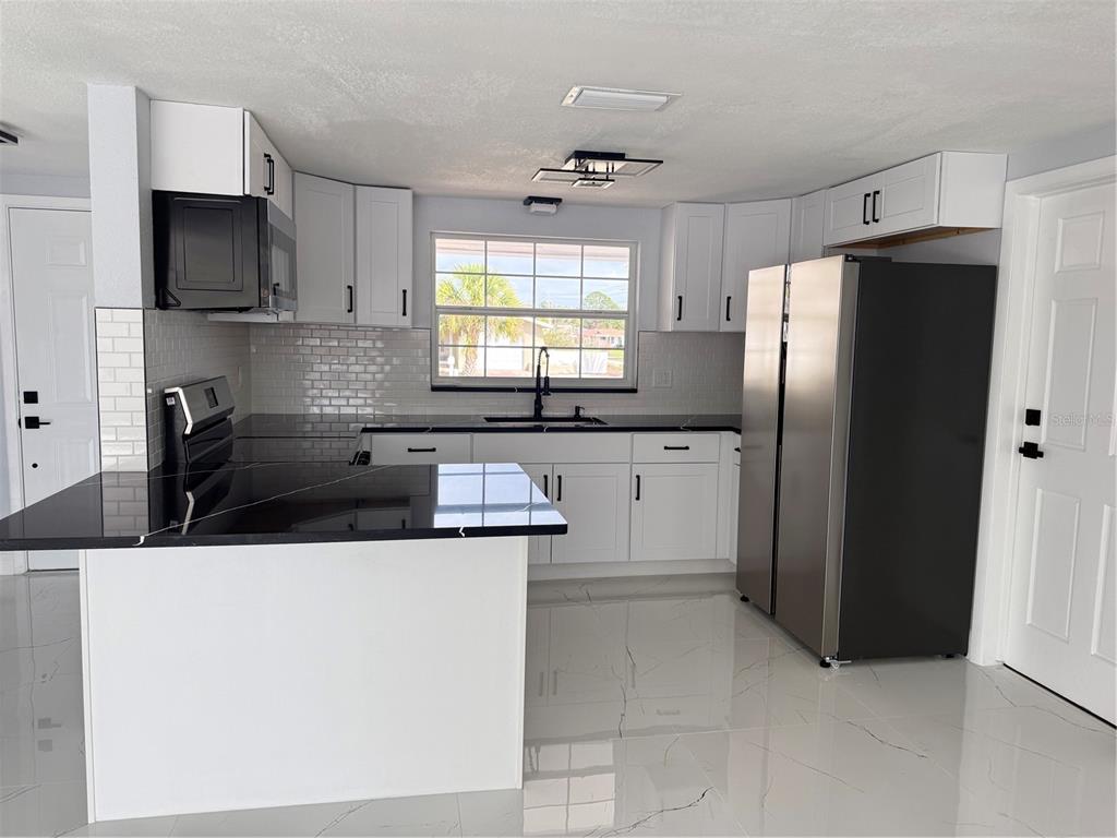 10433 Laburnum Drive Port Richey, FL 34668 - Photo 18 of 26 a kitchen with stainless steel appliances a sink a stove a refrigerator a microwave and cabinets