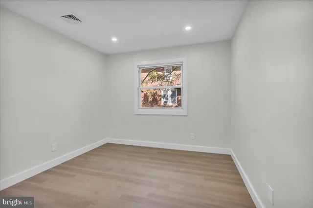 an empty room with wooden floor and window