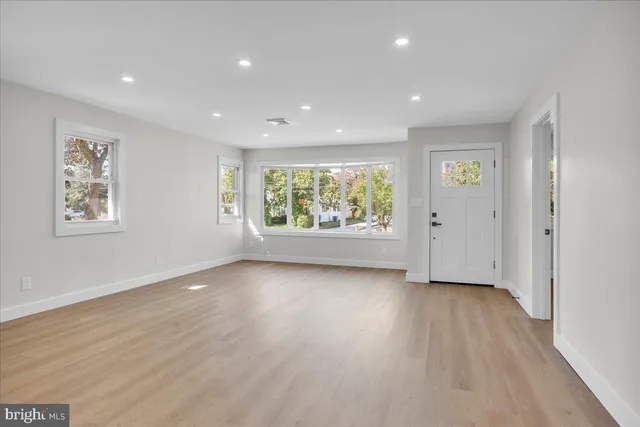 a view of an empty room with wooden floor and windows