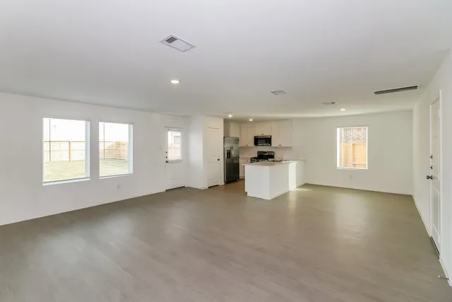 a view of an empty room with a window and wooden floor