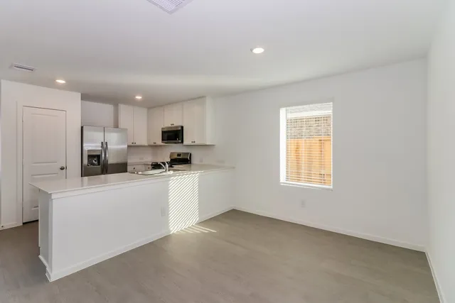 a kitchen with stainless steel appliances granite countertop a stove a sink a refrigerator white cabinets and a refrigerator