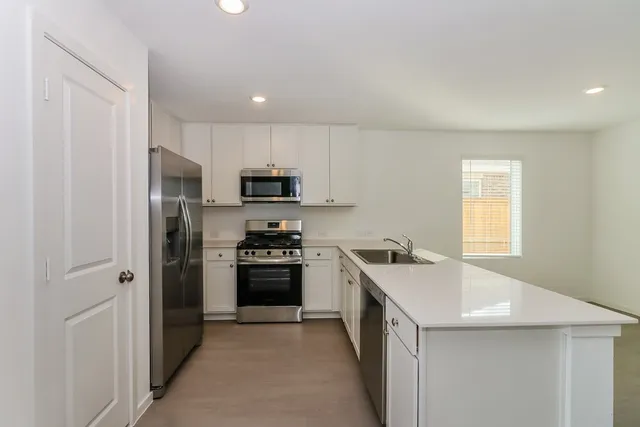 a kitchen with stainless steel appliances a sink stove refrigerator and cabinets
