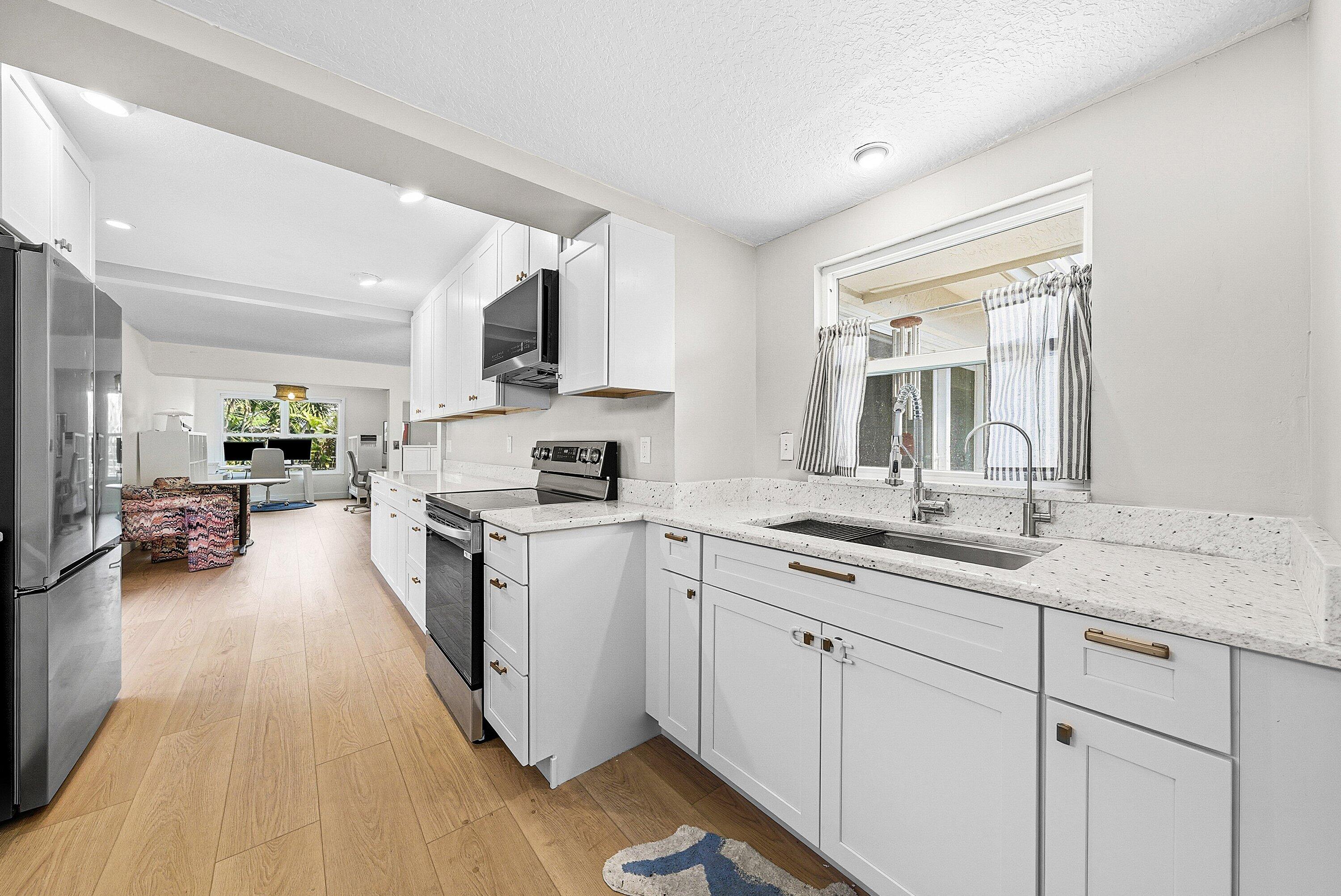 435 Northeast 35th Street Boca Raton, FL 33431 - Photo 22 of 62 a kitchen with a sink dishwasher stove and white cabinets with wooden floor