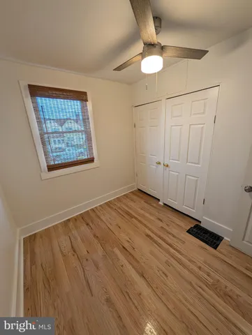 an empty room with wooden floor fan and windows
