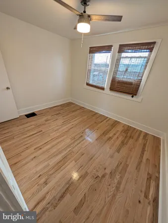 an empty room with wooden floor chandelier and windows