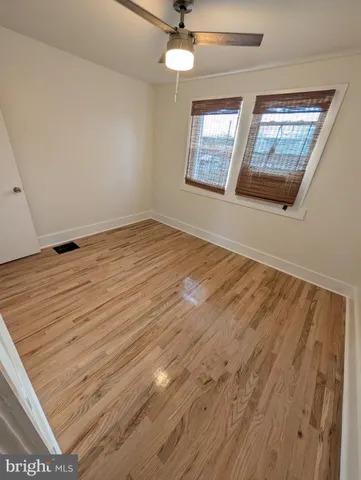 an empty room with wooden floor chandelier and windows