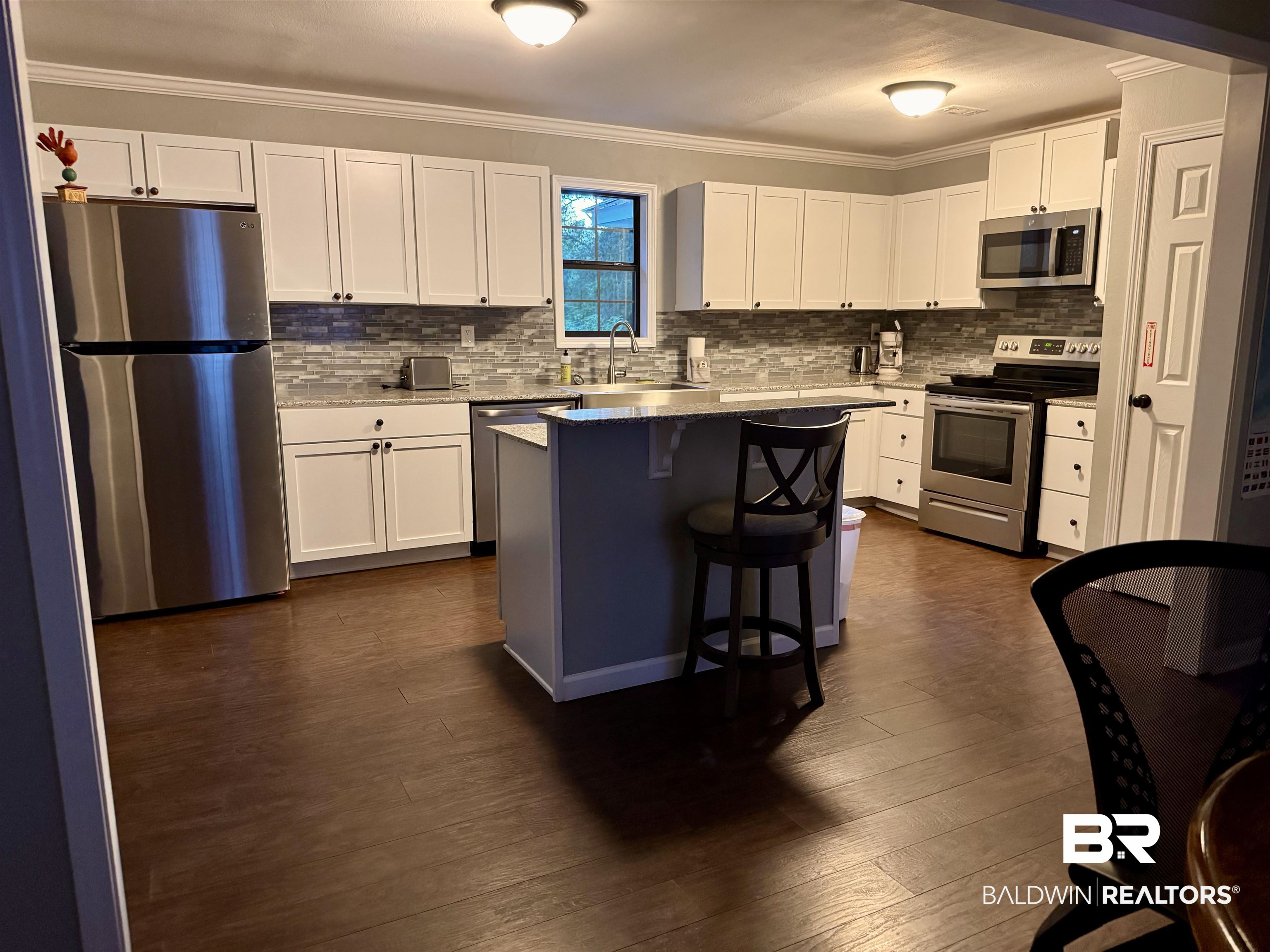 1302 Oak Street Daphne, AL 36526 - Photo 7 of 34 Kitchen featuring stainless steel appliances, white cabinets, a breakfast bar area, dark wood-style floors, and ornamental molding