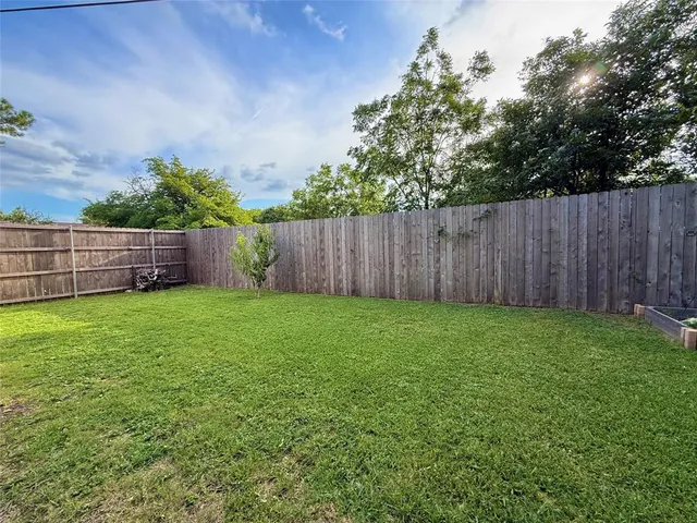 a view of a backyard with a plants and wooden fence