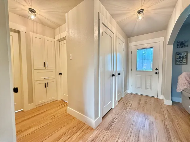 a view of a hallway with wooden floor and a bathroom