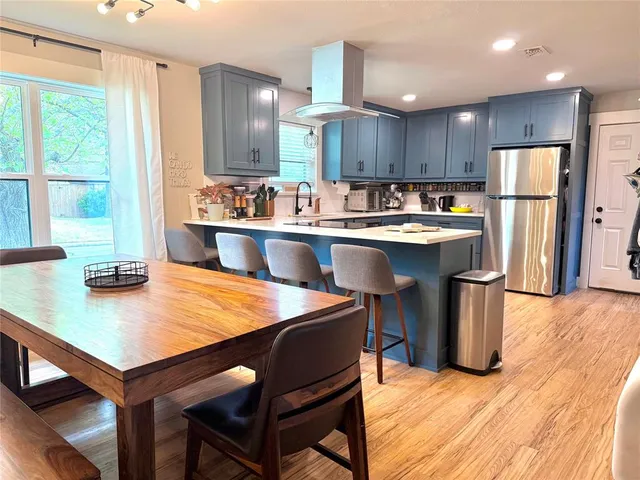 a kitchen with stainless steel appliances granite countertop a table chairs sink refrigerator and cabinets