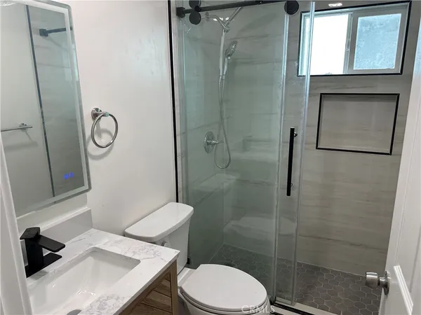 a bathroom with a granite countertop toilet a sink and shower