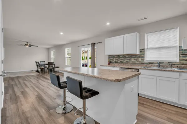 a kitchen with granite countertop white cabinets stove top oven and sink