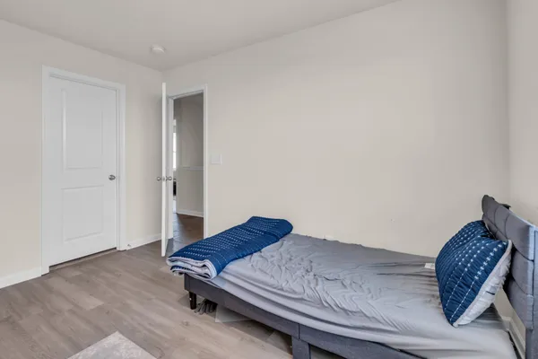 a living room with a bed and a wooden floor
