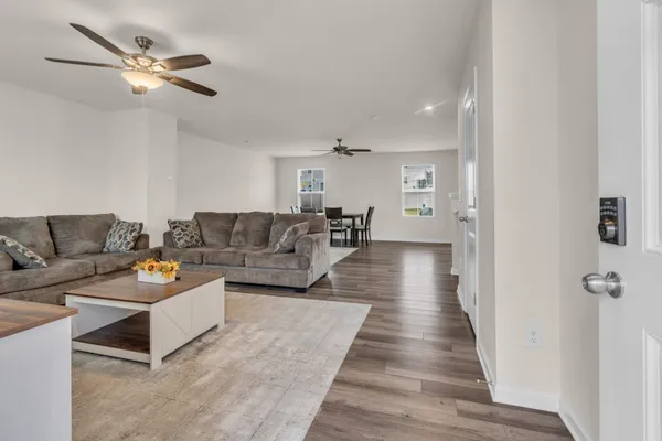 a living room with couches and kitchen view with wooden floor