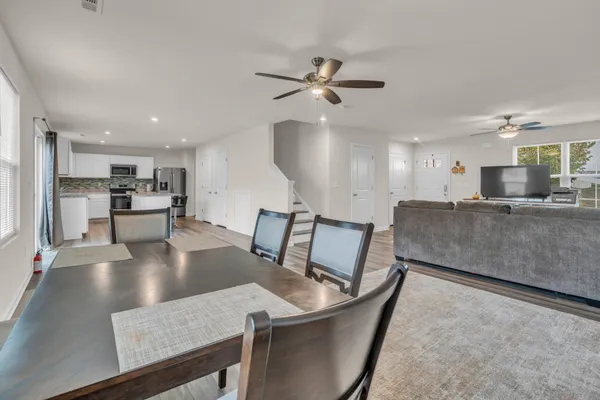 a kitchen with stainless steel appliances granite countertop a sink dishwasher and a refrigerator with wooden floor
