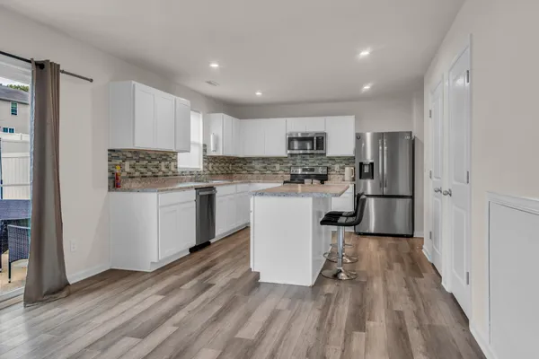 a kitchen with a refrigerator a white stove top oven and white cabinets