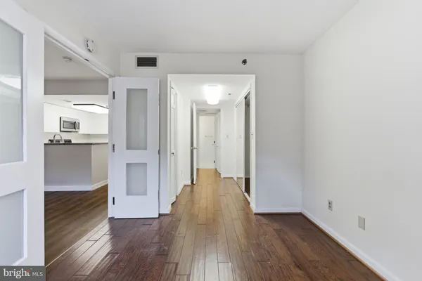 a view of a big room with wooden floor and a kitchen