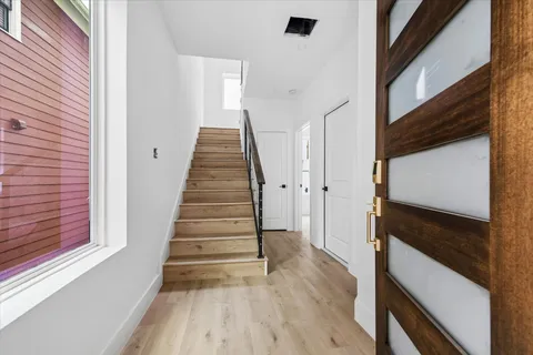 a view of an empty room with wooden floor and closet