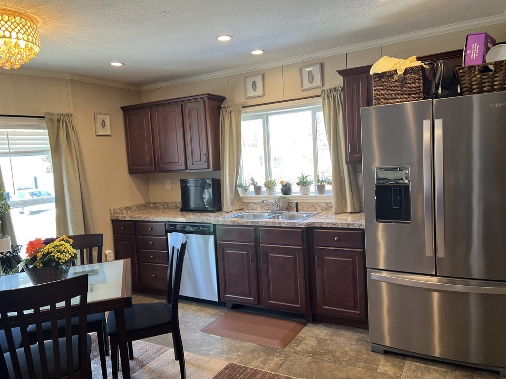 28 Grappone Drive Concord, NH 03301 - Photo 7 of 20 a kitchen with stainless steel appliances granite countertop a refrigerator a sink dishwasher a stove a dining table and chairs with wooden floor