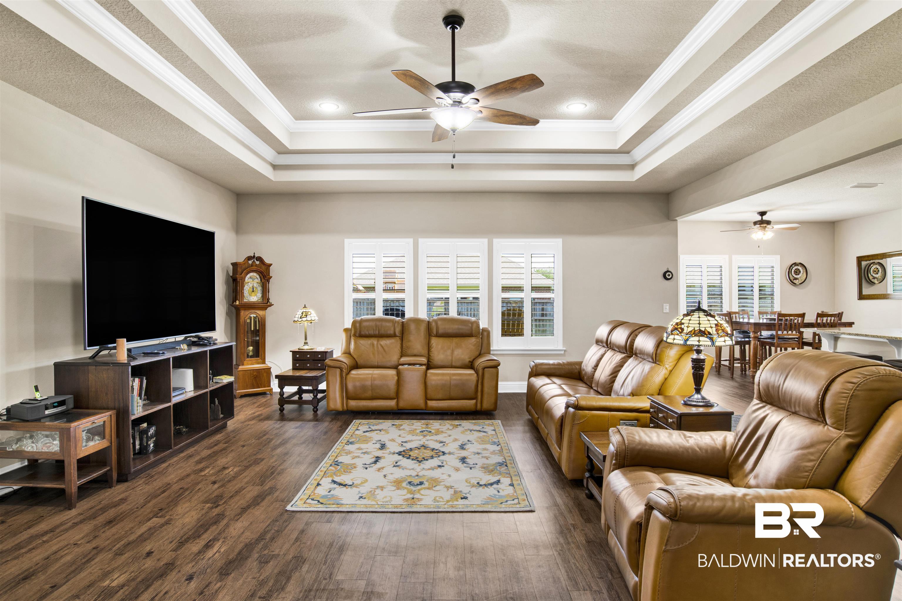 278 Silo Loop Fairhope, AL 36532 - Photo 3 of 26 Living area with ceiling fan, a raised ceiling, dark wood-style flooring, and crown molding