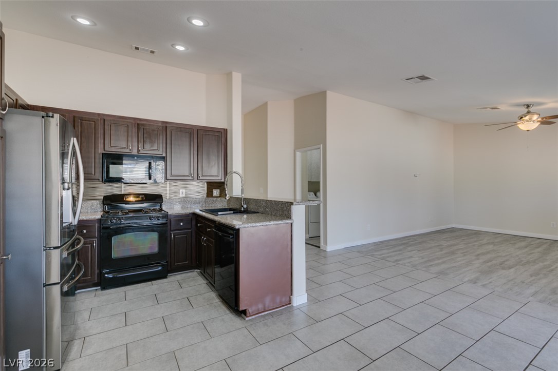 2028 Rustler Ridge Avenue North Las Vegas, NV 89031 - Photo 19 of 40 An open-concept living area boasts a modern kitchen with granite countertops and stainless steel appliances.