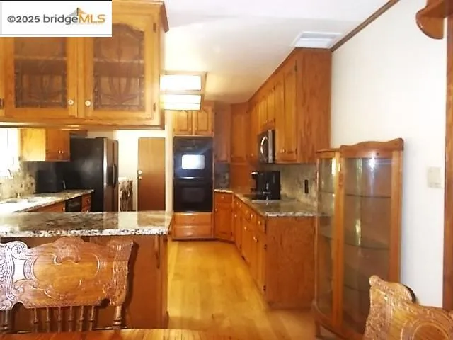 a view of a kitchen with stainless steel appliances granite countertop a sink and cabinets
