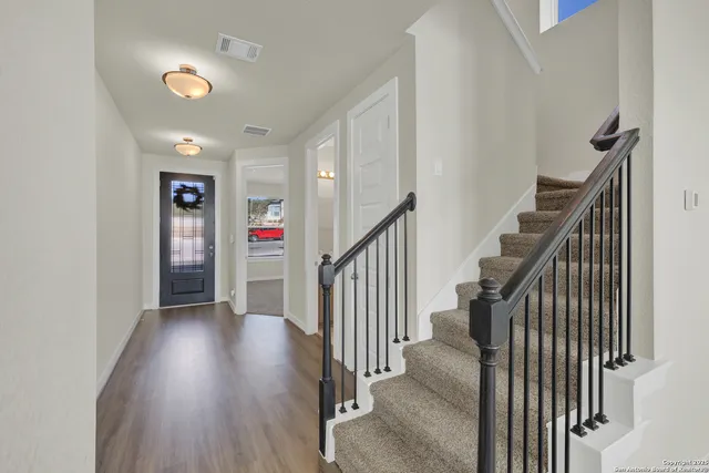 a view of a hallway with wooden floor and stairs