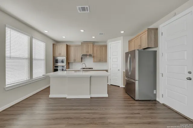 a kitchen with refrigerator and wooden floor