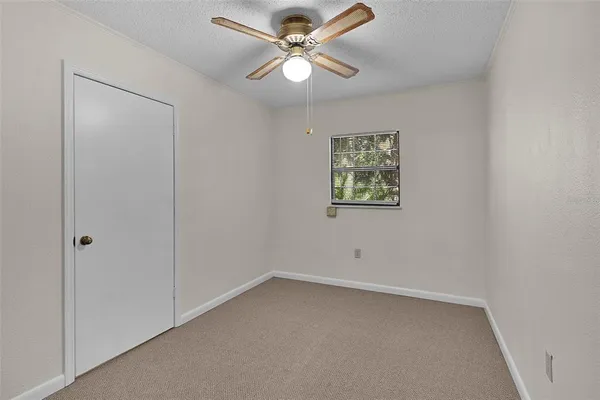 an empty room with a window and a fan