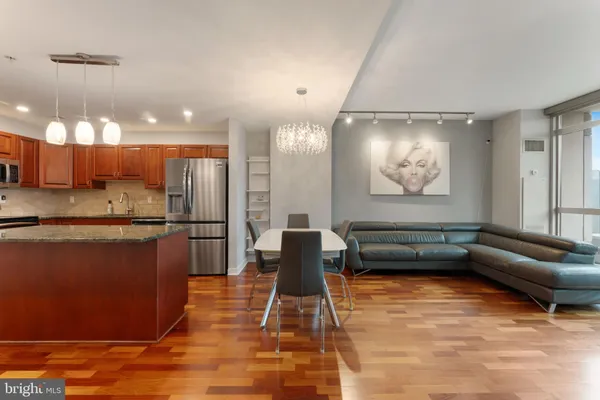 a living room with stainless steel appliances kitchen island granite countertop furniture and a wooden floor