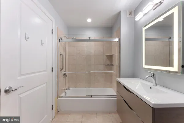 a bathroom with a tub sink shower and mirror