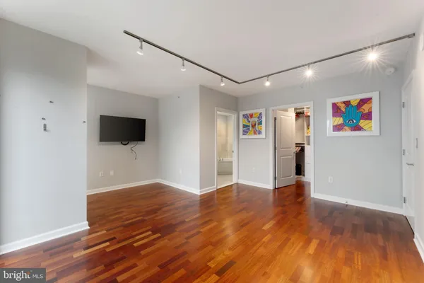 a view of an empty room with wooden floor and a flat screen tv