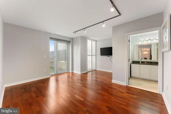 a view of an empty room with window and wooden floor