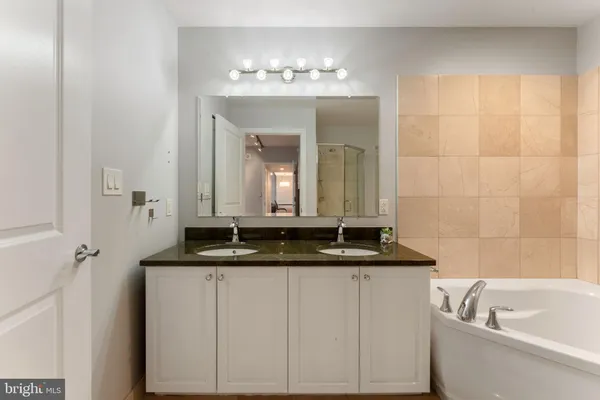 a bathroom with a granite countertop sink a large mirror and a bathtub