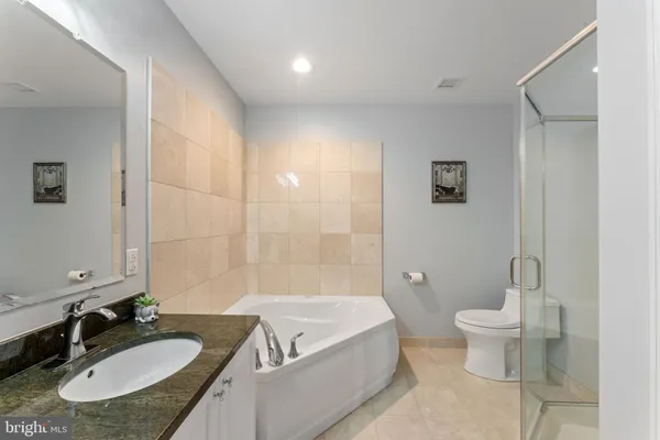 a bathroom with a granite countertop sink a toilet a mirror and shower
