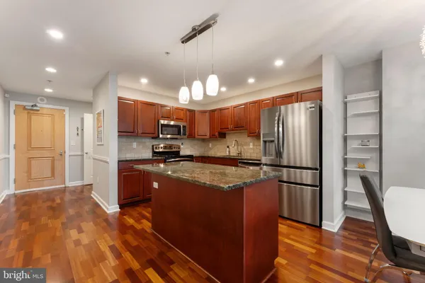 a kitchen with stainless steel appliances granite countertop a refrigerator a sink dishwasher a stove and a refrigerator with wooden floor