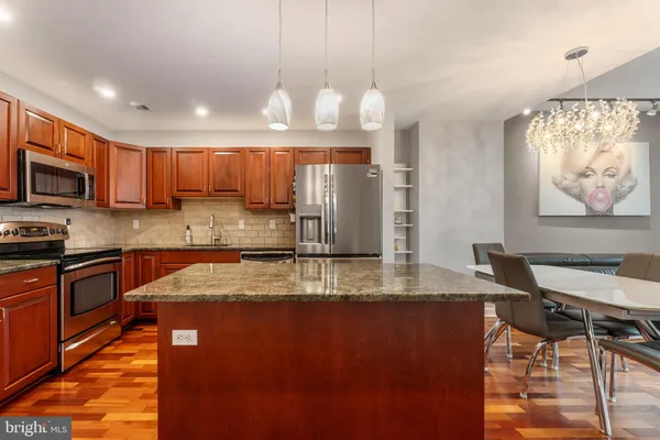 a kitchen with kitchen island granite countertop wooden cabinets a stove a oven a sink with a dining table and chairs