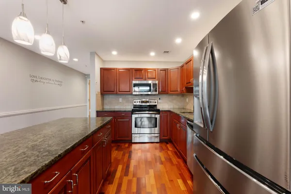 a kitchen with stainless steel appliances granite countertop a refrigerator a sink and a stove