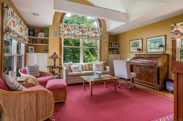 a living room with furniture a flat screen tv and a floor to ceiling window